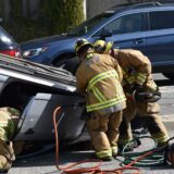 firemen tend to an overturned car following an auto accident