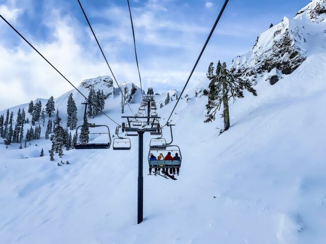 skiers and snowboarders sit on a chairlift