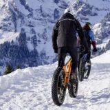 Two cyclists biking on a snowy mountain